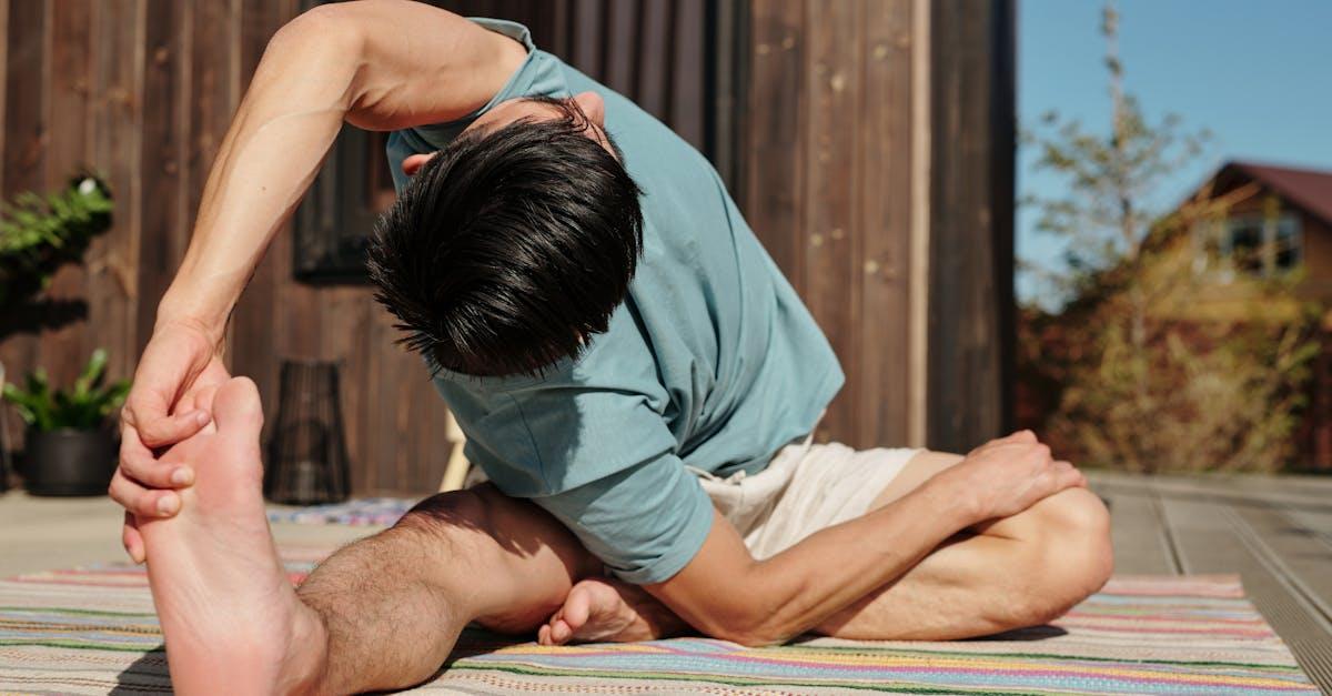 A man performs a yoga stretch on a colorful mat outdoors under the sun, promoting wellness.